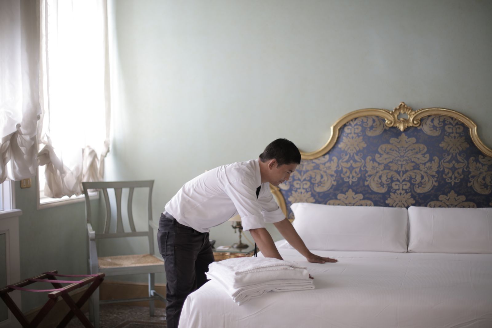 Luxe housekeeper adjusting bed linens in a luxury bedroom